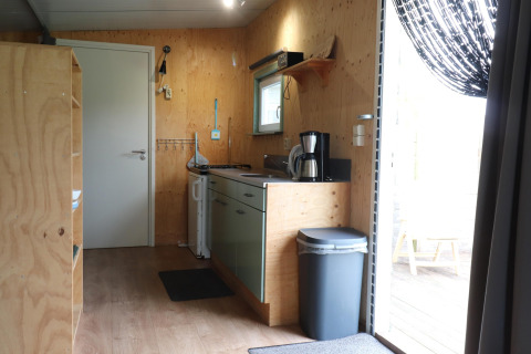 Intérieur d'une cuisine chaleureuse avec murs en bois et cafetière dans un lodge aux Pays-Bas.