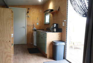 Intérieur d'une cuisine chaleureuse avec murs en bois et cafetière dans un lodge aux Pays-Bas.