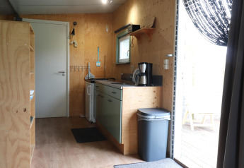 Intérieur d'une cuisine chaleureuse avec murs en bois et cafetière dans un lodge aux Pays-Bas.