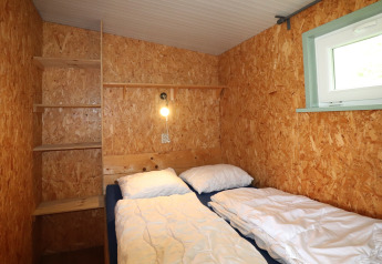 Kleine, gezellige slaapkamer in Cosy cabin 1 in Nederland met houten wanden en twee bedden.