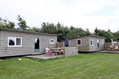Deux cabanes en bois avec coins salon extérieurs à Cosy cabin 1, Pays-Bas, pelouse verte au premier plan.