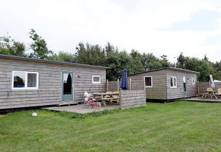 Deux cabanes en bois avec coins salon extérieurs à Cosy cabin 1, Pays-Bas, pelouse verte au premier plan.