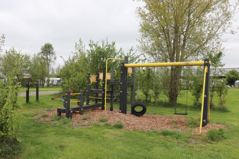 Aire de jeux avec balançoires et structure d’escalade près de Cosy cabin 1 aux Pays-Bas, arbres autour.