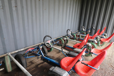 Quatre karts à pédales rouges sont garés sous un abri au lodge Cosy cabin 1 aux Pays-Bas.