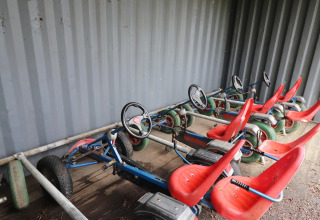 Quatre karts à pédales rouges sont garés sous un abri au lodge Cosy cabin 1 aux Pays-Bas.