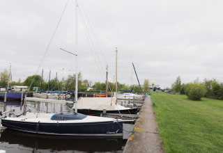 Voiliers amarrés au quai près d’une pelouse à la Cosy cabin 1 aux Pays-Bas.