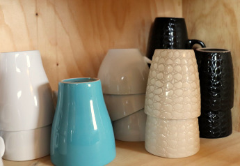 Keramische mokken in verschillende kleuren en texturen opgestapeld op een houten plank in Cosy cabin 1, Nederland.