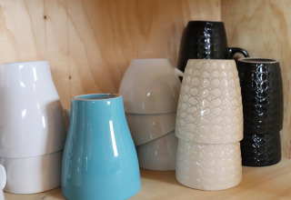 Tasses en céramique de différentes couleurs et textures empilées sur une étagère en bois, Cosy cabin 1, Pays-Bas.