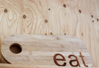 Houten snijplank met 'eat' erop, gefotografeerd in de houten Cosy cabin 1 in Nederland.