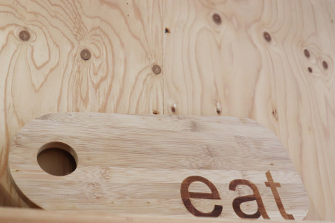 Planche à découper en bois gravée 'eat', photographiée dans Cosy cabin 1 aux Pays-Bas, intérieur en bois.