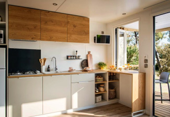 Modern kitchen interior in 'Terrace Lodge 2' chalet in the Netherlands, featuring open shelving and light.