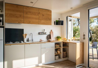Modern kitchen interior in 'Terrace Lodge 2' chalet in the Netherlands, featuring open shelving and light.