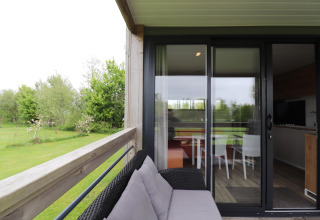 View from the Terrace Lodge 2 chalet in the Netherlands with outdoor seating and glass sliding door inside.