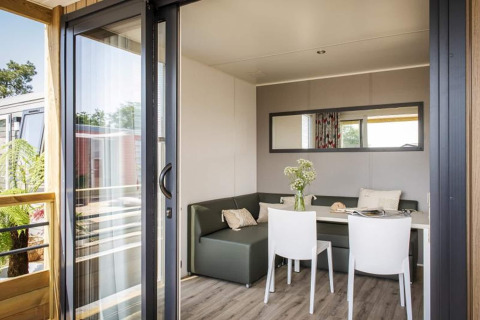 Modern living area in Terrace Lodge 2, Netherlands, with sofa, dining table, flowers, and large sliding door.