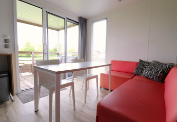 Lichte, moderne leefruimte in Terrace Lodge 2, Nederland, met eettafel, roze bank en uitzicht op het balkon.
