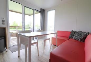 Heller, moderner Wohnbereich in Terrace Lodge 2 mit Esstisch, rosa Sofa und Blick auf den Balkon in Holland.
