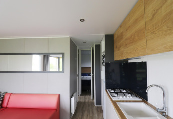 Modernes Chalet-Innere im Terrace Lodge 2, Niederlande, mit Wohnzimmer, Küche und Blick ins Schlafzimmer.