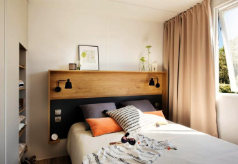 Modern ingerichte slaapkamer in Terrace Lodge 2, Nederland, met bed, houten hoofdbord en raam.