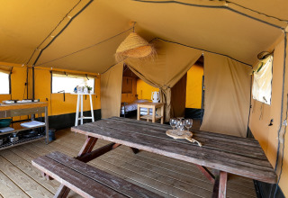 Innenansicht des Safari-Zeltes Heeg für 4 Personen mit Holztisch und Küchenbereich in den Niederlanden.