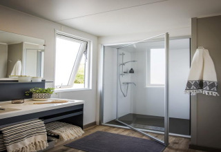 Modern bathroom in the Terrace lodge 2 chalet in the Netherlands featuring glass shower and large windows.
