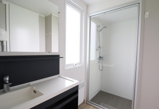 Modern bathroom with shower, large mirror, and sink at Terrace Lodge 2 chalet in the Netherlands.