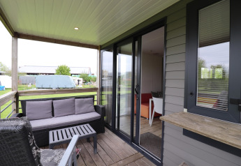 Terrasse mit Sitzbereich der Terrace Lodge 2, mit Blick auf Garten und Felder in den Niederlanden.