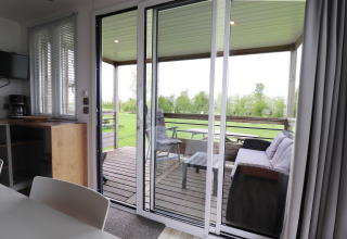 View from living room to covered terrace with sofa and table at Terrace Lodge 2, Netherlands.