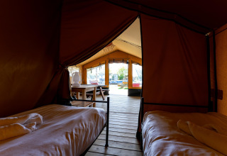 Innenaufnahme eines Safari-Zeltes in den Niederlanden mit zwei Betten und einem Blick auf die Terrasse.