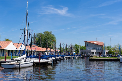 Ein Hafen mit Segelbooten und Gebäuden mit roten Dächern, aufgenommen am Safari-Zelt Heeg, Niederlande.