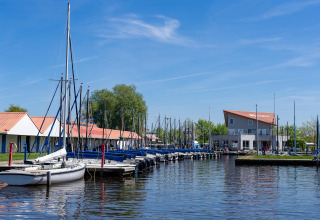 Ein Hafen mit Segelbooten und Gebäuden mit roten Dächern, aufgenommen am Safari-Zelt Heeg, Niederlande.