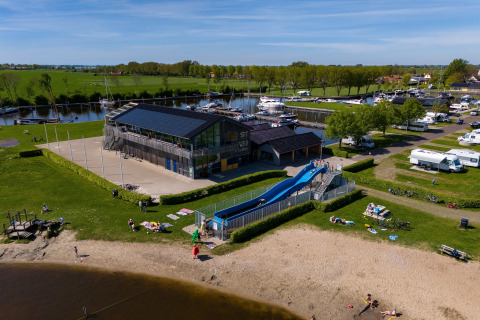 Luftaufnahme eines Safarizeltplatzes in Heeg, Niederlande, mit Wasserrutsche, Strand und Yachthafen.