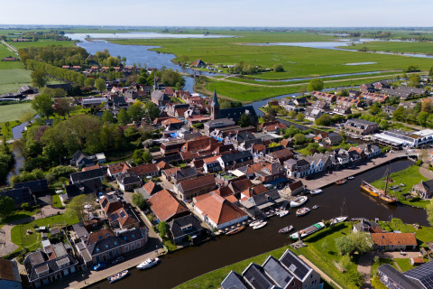 Luftaufnahme von Heeg in den Niederlanden mit Kanälen, Booten und grüner Landschaft im Sommer.