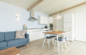 Luminoso salón-cocina moderno en Sea Lodges Ameland 4, con mesa de comedor, sofá y decoración escandinava.