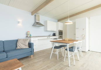 Luminoso salón-cocina moderno en Sea Lodges Ameland 4, con mesa de comedor, sofá y decoración escandinava.