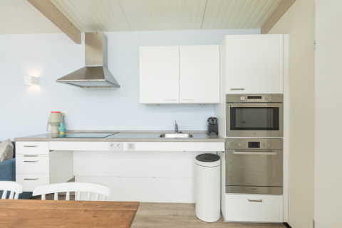 Moderne keuken in strandhuis Sea Lodges Ameland 4 in Nederland, met witte kasten en toestellen.