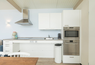 Moderne keuken in strandhuis Sea Lodges Ameland 4 in Nederland, met witte kasten en toestellen.