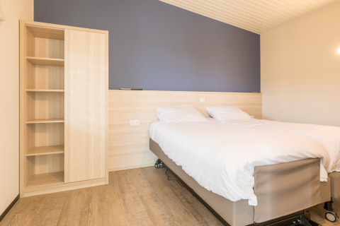 Lichte slaapkamer met tweepersoonsbed en kast in Sea Lodges Ameland 4 strandhuis in Nederland.