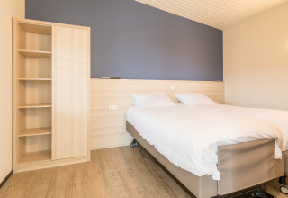 Lichte slaapkamer met tweepersoonsbed en kast in Sea Lodges Ameland 4 strandhuis in Nederland.