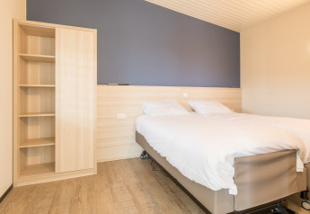 Dormitorio luminoso con cama doble y armario en Sea Lodges Ameland 4, casa de playa en los Países Bajos.