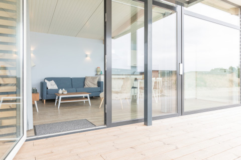Lichte zithoek in Sea Lodges Ameland 4 strandhuis, met sofa, tafel en grote glazen deur naar het terras.