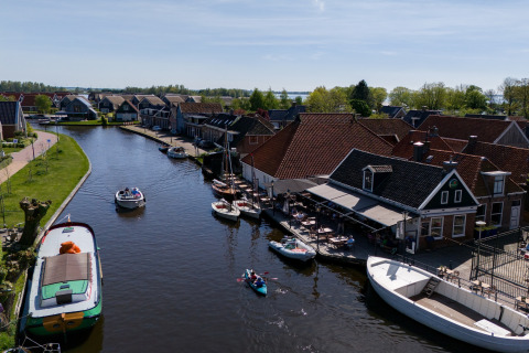 Blick auf einen Kanal mit Booten und Häusern bei Safari Tent Heeg in den Niederlanden an einem sonnigen Tag.