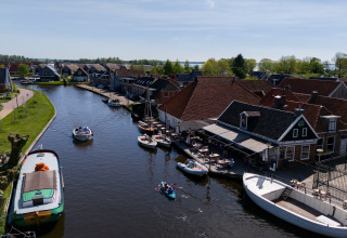 Blick auf einen Kanal mit Booten und Häusern bei Safari Tent Heeg in den Niederlanden an einem sonnigen Tag.