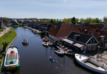 Udsigt over kanal med både og huse ved Safari Tent Heeg i Holland, idyllisk og solrig dag.