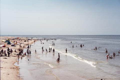 Op het strand genieten mensen van het mooie weer, spelend in het water en rustend op het zand.