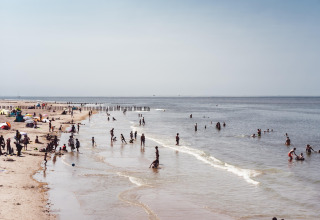 Op het strand genieten mensen van het mooie weer, spelend in het water en rustend op het zand.