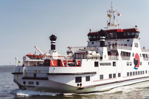 Een grote Wagenborg-veerboot met de naam SIER vaart over zee met passagiers en auto's aan boord.