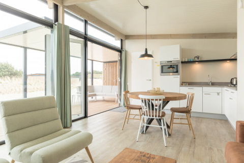 Lichte, moderne leefruimte met open keuken en eetruimte in strandhuis Sea Lodges Ameland 3, Nederland.
