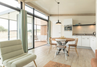 Lichte, moderne leefruimte met open keuken en eetruimte in strandhuis Sea Lodges Ameland 3, Nederland.