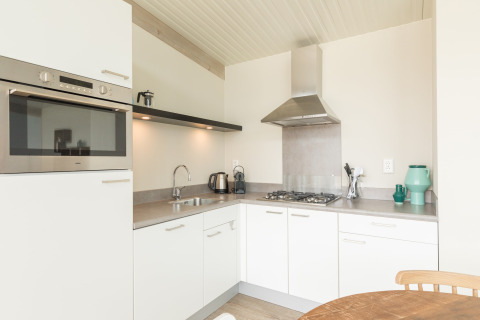 Moderne keuken met witte kasten, oven en gasfornuis bij Sea Lodges Ameland 3 in Nederland.