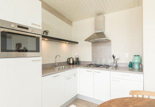Moderne keuken met witte kasten, oven en gasfornuis bij Sea Lodges Ameland 3 in Nederland.